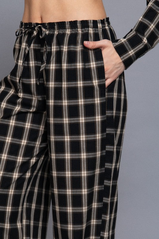 Black tartan plaid pants close-up showing the drawstring waistband and side pocket.