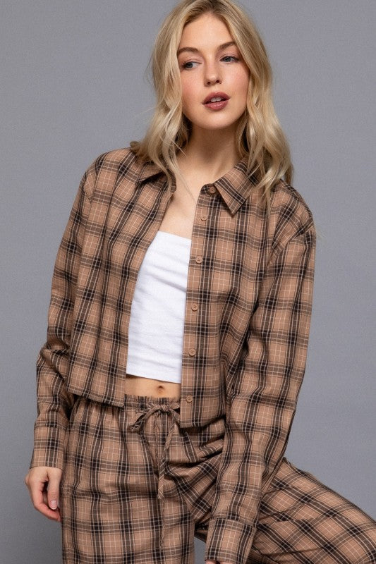 Beige tartan plaid cropped shirt worn open over a white top, seated view.