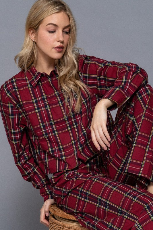 Red tartan plaid matching set with a buttoned cropped shirt and wide-leg pants, seated view.